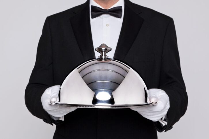 waiter serving a meal under a silver cloche