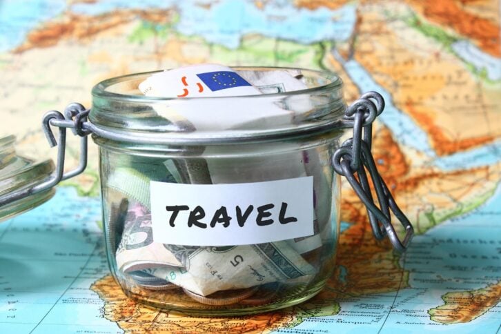 vacation money savings in a glass jar on world map
