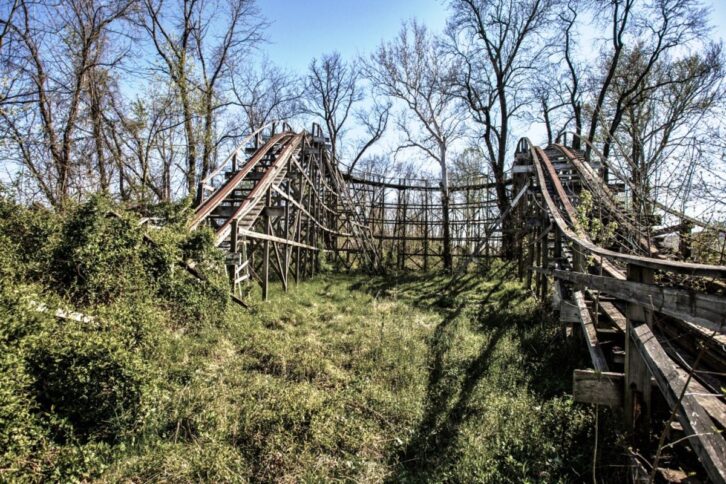 Abandoned Williams Grove Amusement Park, Cumberland County, Pennsylvania, dramatic view of a small roller coaster with overgrown plants, bare trees with a blue sky