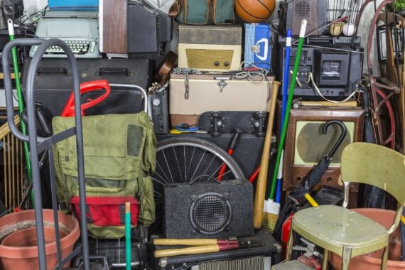 An assortment of vintage items in a personal garage, including chairs, exercise and gardening equipment, and more
