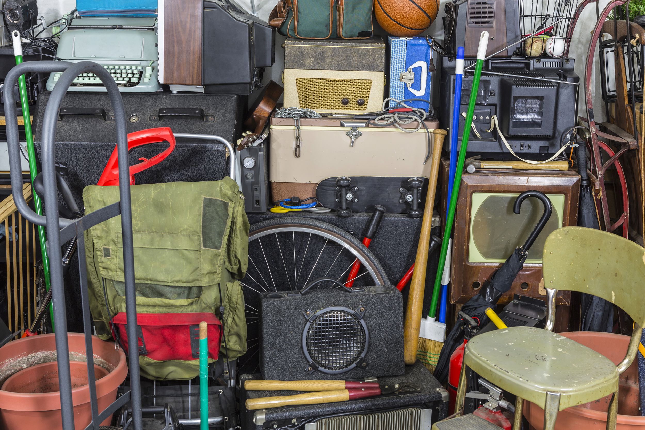 An assortment of vintage items in a personal garage, including chairs, exercise and gardening equipment, and more