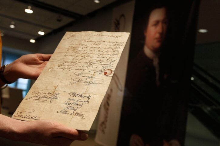 An autograph letter by Declaration of Independence signer, Button Gwinnett (pictured, background) is seen at Sotheby's auction house April 8, 2010 in New York