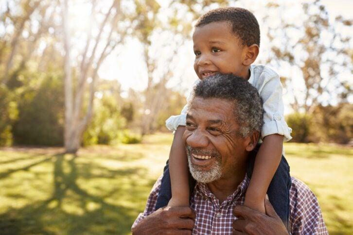 Young boy sitting on his grandfather's shoulders