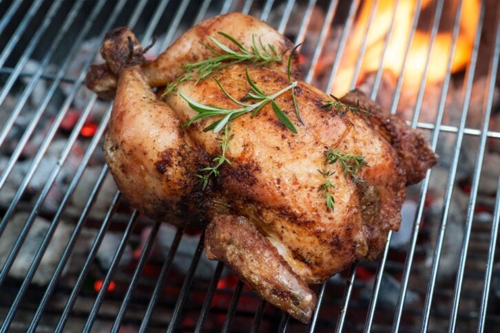 Whole chicken on the grill with parsley sprigs