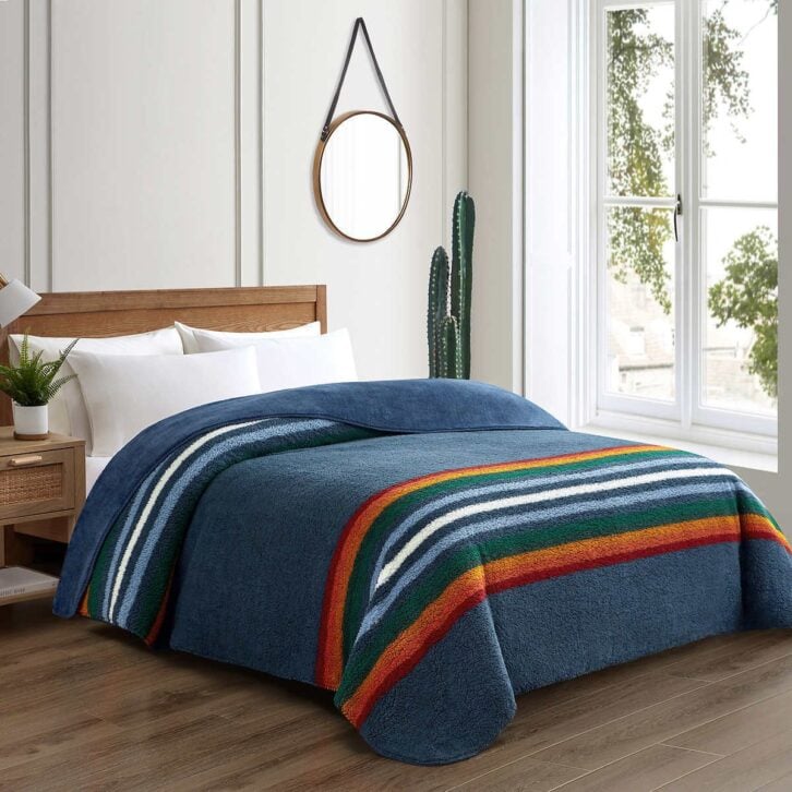Bedroom displaying blue Pendleton-brand plush blanket on bed
