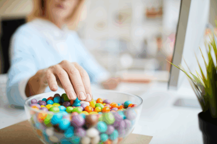 woman sticking hand into a candy bowl
