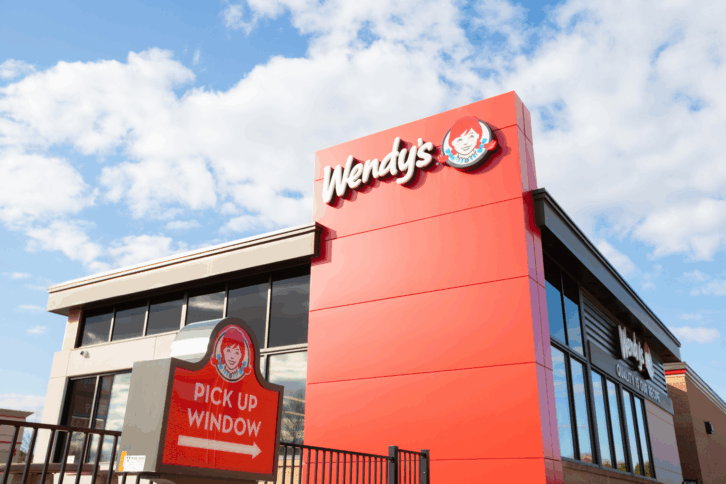 Front exterior of Wendy's fast food restaurant, Hamilton, Ontario, Canada, drive thru sign in foreground, building against a blue sky with white clouds