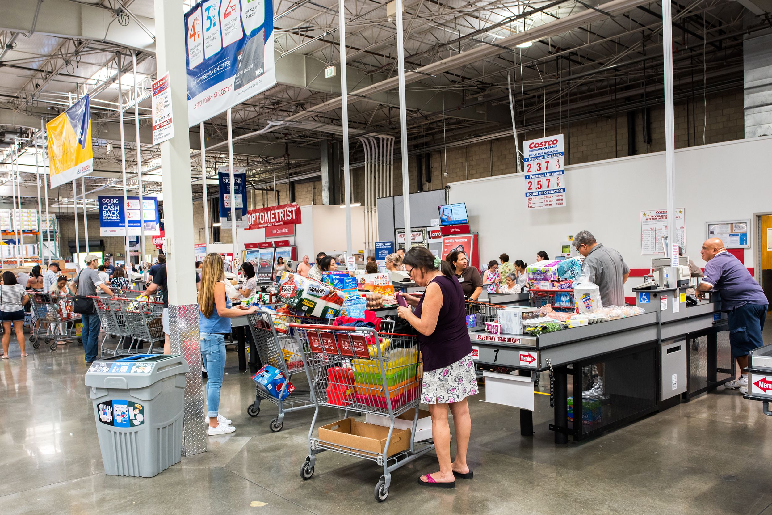 Woman unloading a full cart at a checkout at Costco.