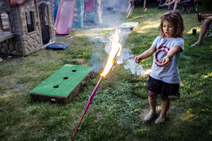 little girl with sparklers at party in yard