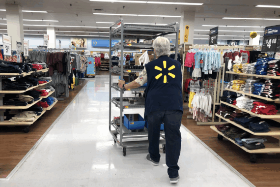 A Walmart employee pushes a cart through a Walmart store
