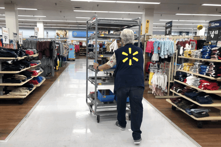 A Walmart employee pushes a cart through a Walmart store
