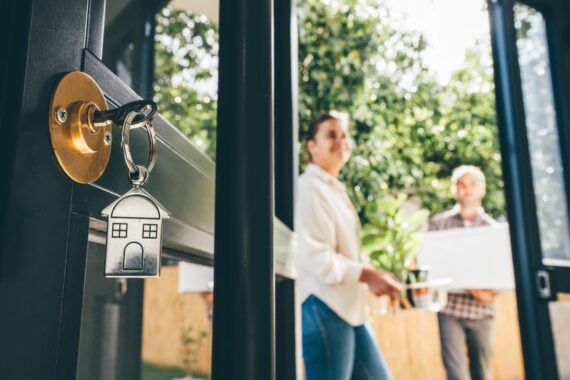 A couple stands outside a door with a new house key in it