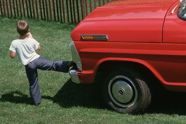 July 1975: A little boy delivers a sideways kick to a red Ford truck in Old Roxbury, Connecticut.