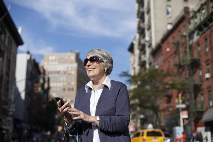senior woman on smartphone in city