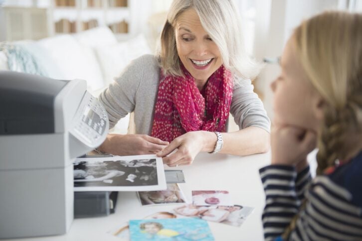 senior Caucasian woman and granddaughter printing photos