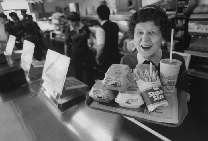A 1998 photo showing an elderly McDonald's worker holding a tray of food and smiling