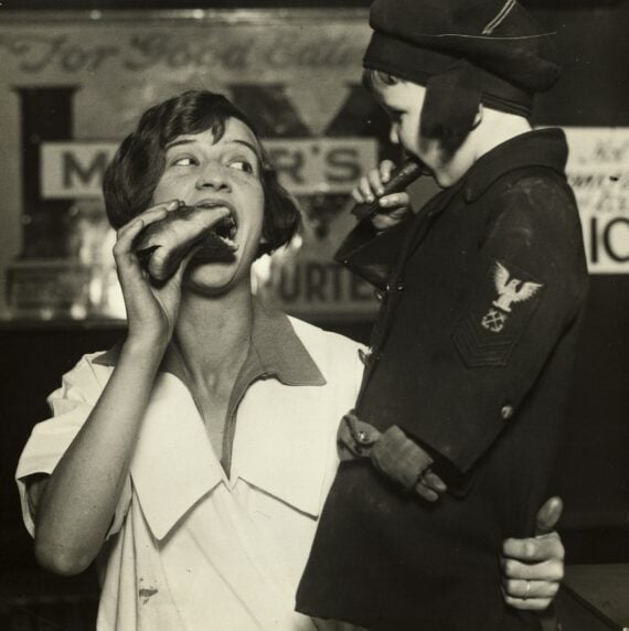 A woman and child enjoying hot dogs in 1926