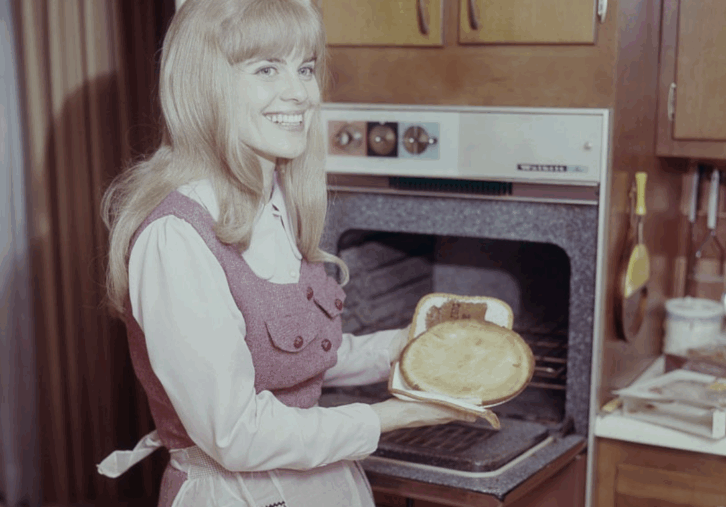 Woman Taking Fresh Pie Out Of Oven Nostalgic