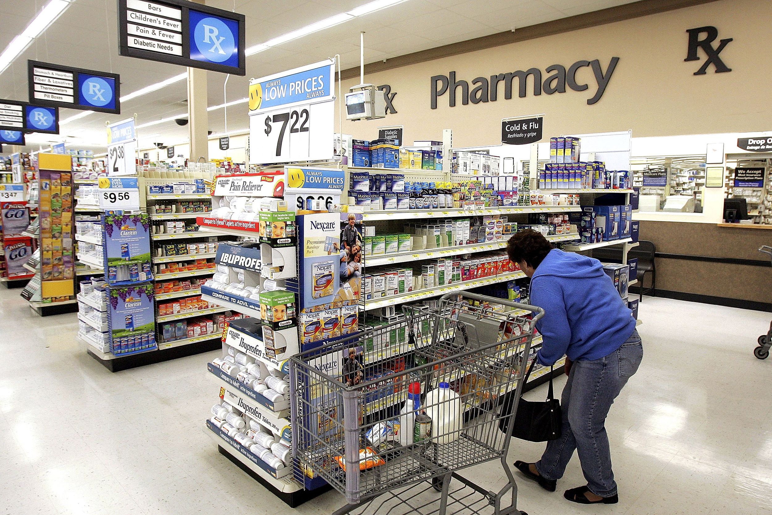 Interior of a brightly lit pharmacy section within a supermarket, with shelves of medications and a Pharmacy sign.