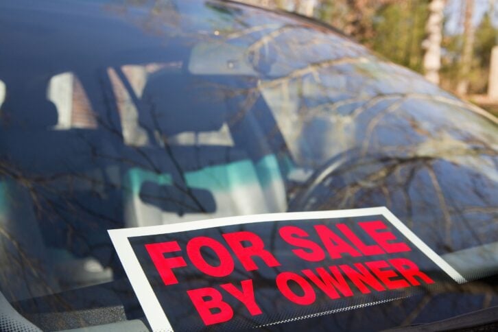 car with sign that reads 'for sale by owner' on dashboard