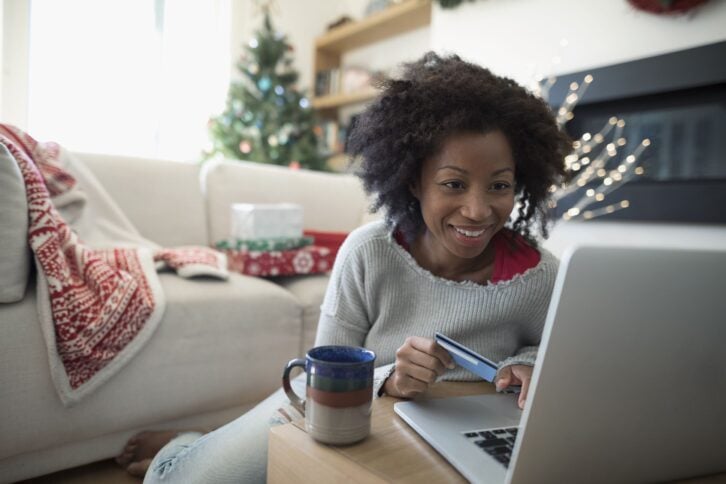 smiling woman with credit card online Christmas shopping at laptop in living room