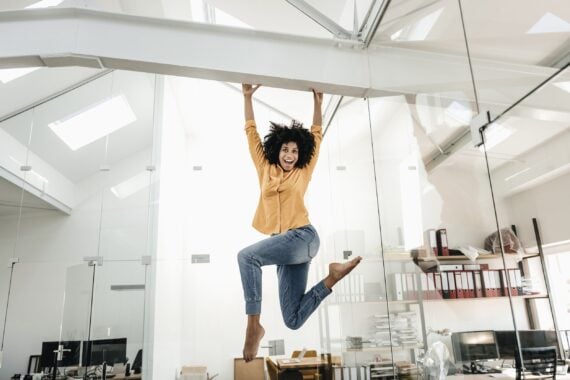 happy young woman hanging on beam in office