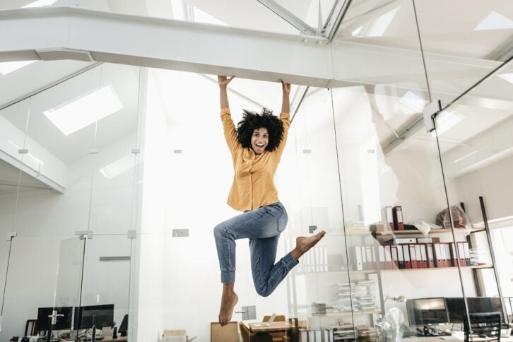 happy young woman hanging on beam in office