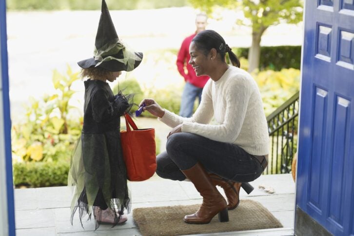 African woman giving candy to trick or treater
