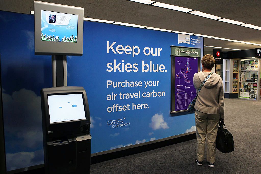 a traveler stands near a new climate passport carbon offset kiosk