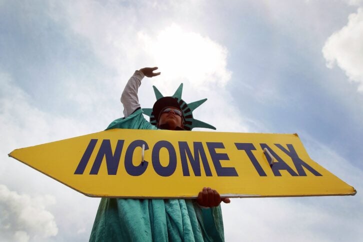 Felipe Castro holds a sign advertising a tax preparation office for people that still need help completing their taxes before the Internal Revenue Service deadline on April 14, 2010 in Miami, Florida