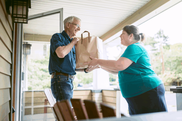 Neighbor bringing groceries to an elderly man
