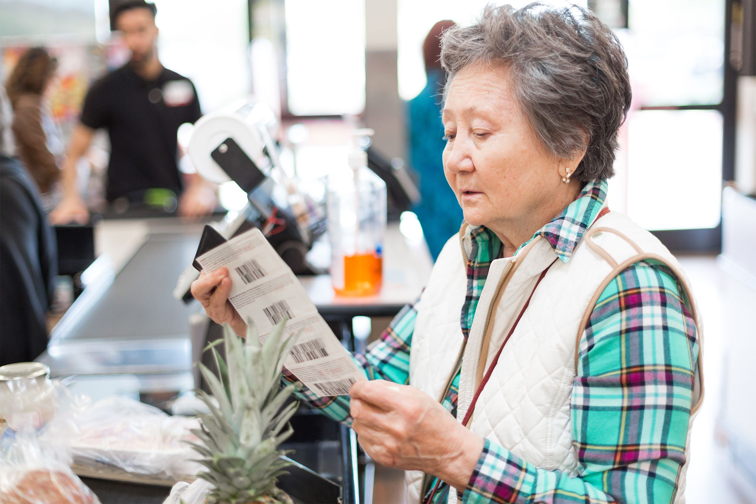 Woman at grocery checkout with coupons