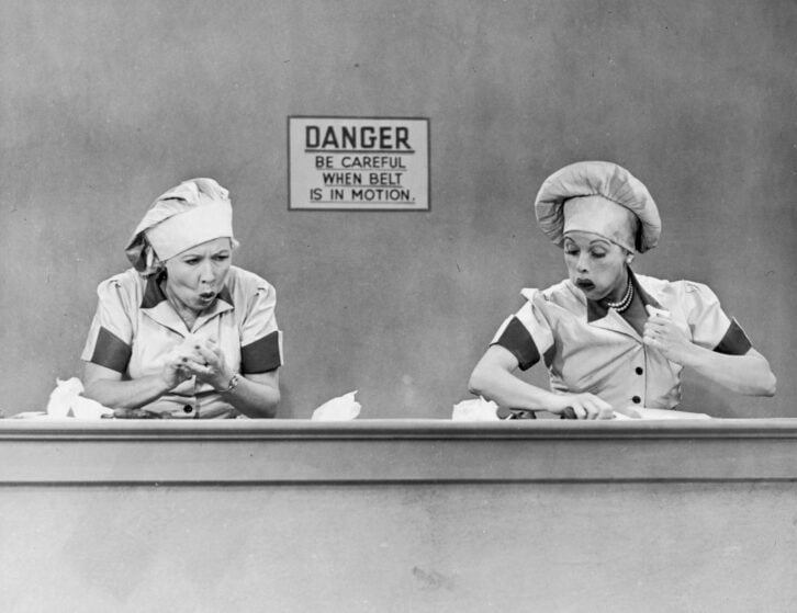 American actresses Vivian Vance (1909 - 1979), as Ethel Mertz, and Lucille Ball (1911 - 1989), as Lucy Ricardo, work side-by side at a candy factory conveyor belt in an episode of the television comedy 'I Love Lucy' entitled 'Job Switching,' Los Angeles,