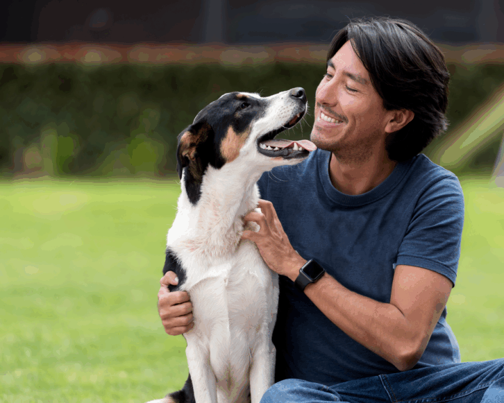 Man sitting outside smiling and holding his dog