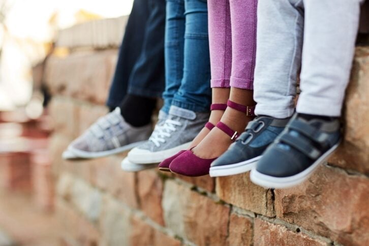 Closeup of kids' shoes with brick wall in background
