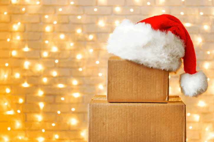 Packages with santa hat and Christmas lights in background