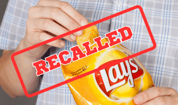Tambov, Russian Federation - January 20, 2013: Hand takes out potato chip from Lay's bag. It is a potato chips with cheese. Recall sign on top
