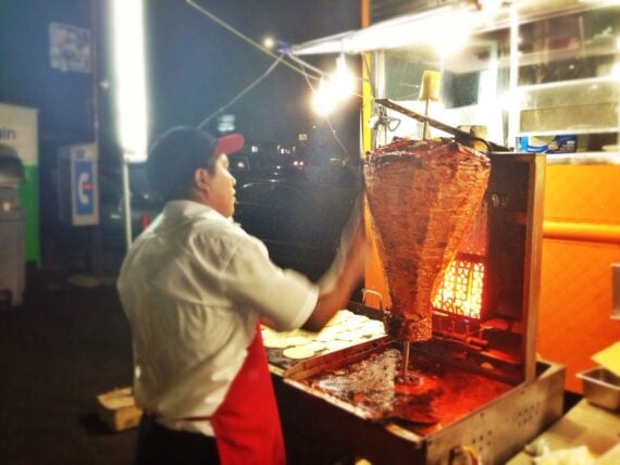 Worker at Leo's Taco Truck shaving meat of al pastor spit in Los Angeles