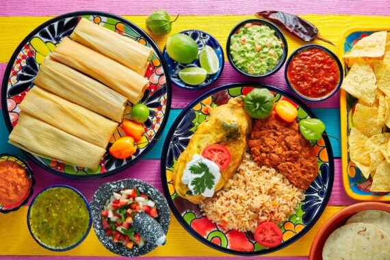 Delicious looking Mexican food on a table with tamales, chips, salsa, and guacamole mmm