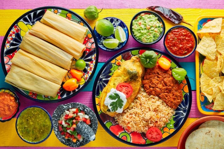 Delicious looking Mexican food on a table with tamales, chips, salsa, and guacamole mmm