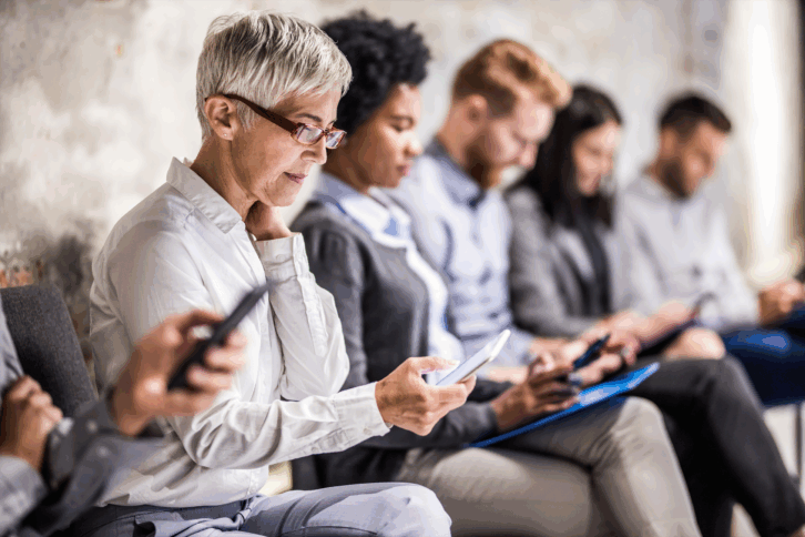 Older woman sitting in line for an interview on her phone