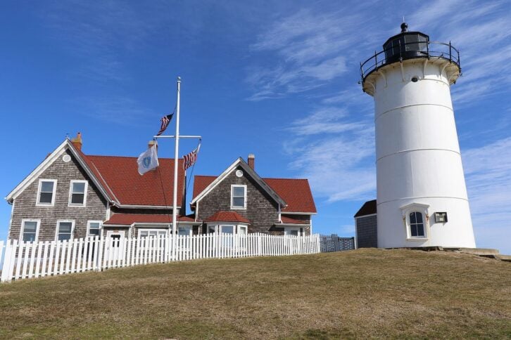 Nobska Lighthouse is a beautiful white lighthouse with a New England style keepers house next to it.