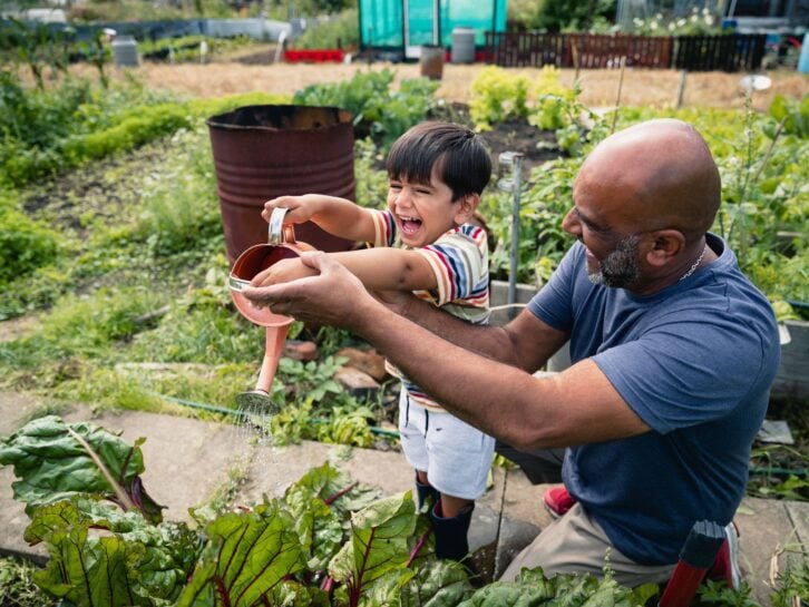 A front view shot of a young grandson helping his grandfather around the garden.
