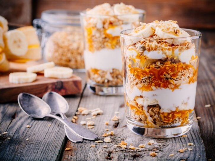 healthy breakfast. homemade granola with natural yoghurt, banana and caramel sauce on wooden background
