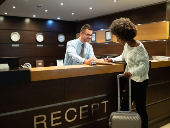 Female tourist arriving in hotel, completing documents.