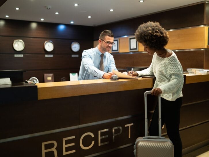 Female tourist arriving in hotel, completing documents.
