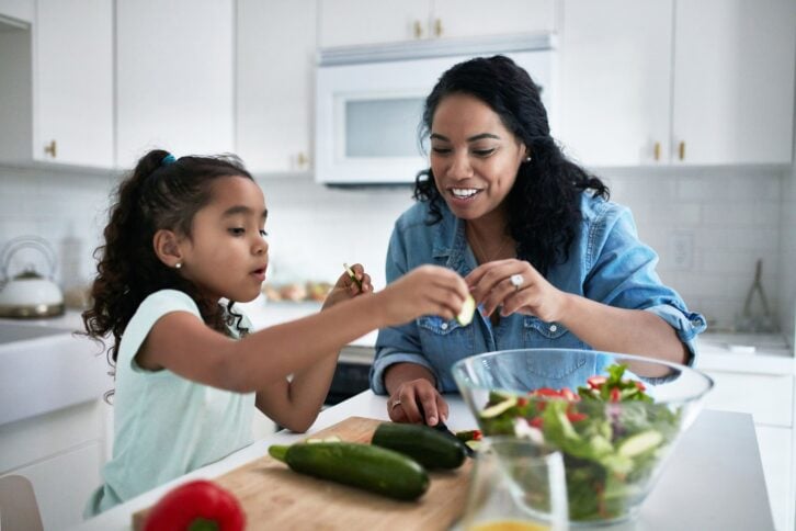 Mother and daughter preparing veggies in kitchen