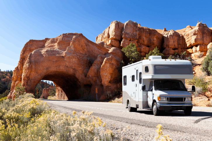 RV parked on road through Bryce Canyon National Park, Utah with canyon tunnel in the background on a bright sunny day