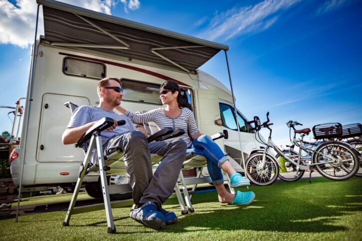 Happy couple sitting outside of their RV