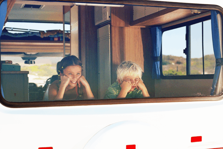 two children looking out back window of rv